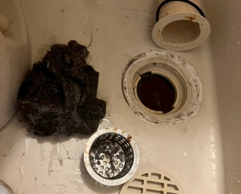浴室排水管から除去された髪の毛と汚れが固着した詰まりの回収物