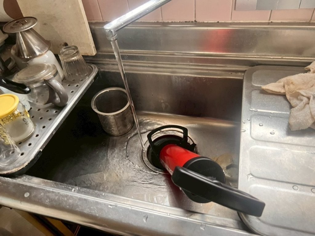 空圧ポンプを使用してキッチン排水口の詰まり除去を行っている施工中の様子