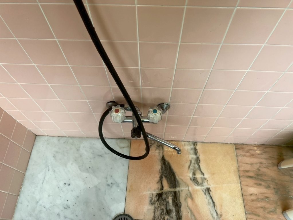 既存浴室混合水栓の設置状態を確認している施工前写真